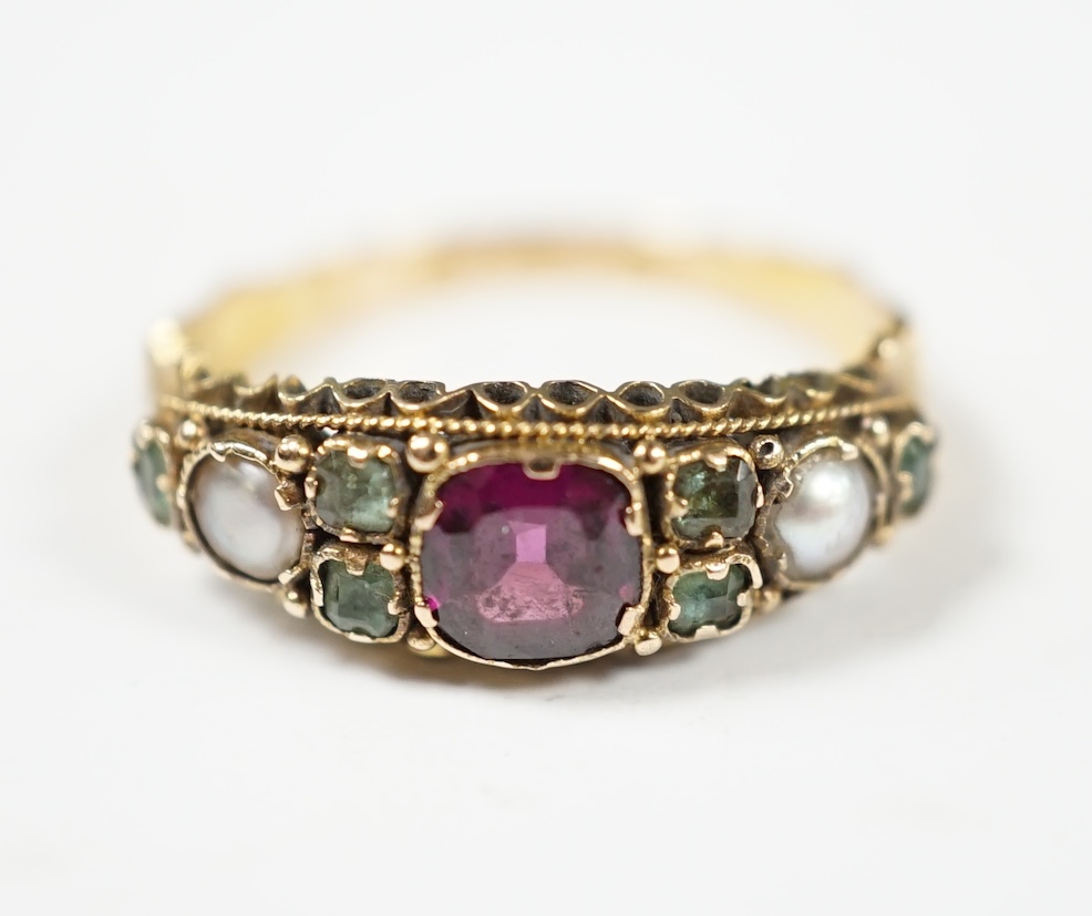 A late Victorian 15ct gold, garnet, emerald and seed pearl cluster set dress ring, in the Suffragette colours, size L/M, gross weight 2.1 grams. Condition - fair to good